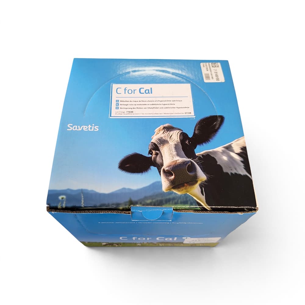 Boîte bleue et blanche de bolus C for Cal pour vaches laitières, accompagnée d'un bolus cylindrique beige au premier plan.