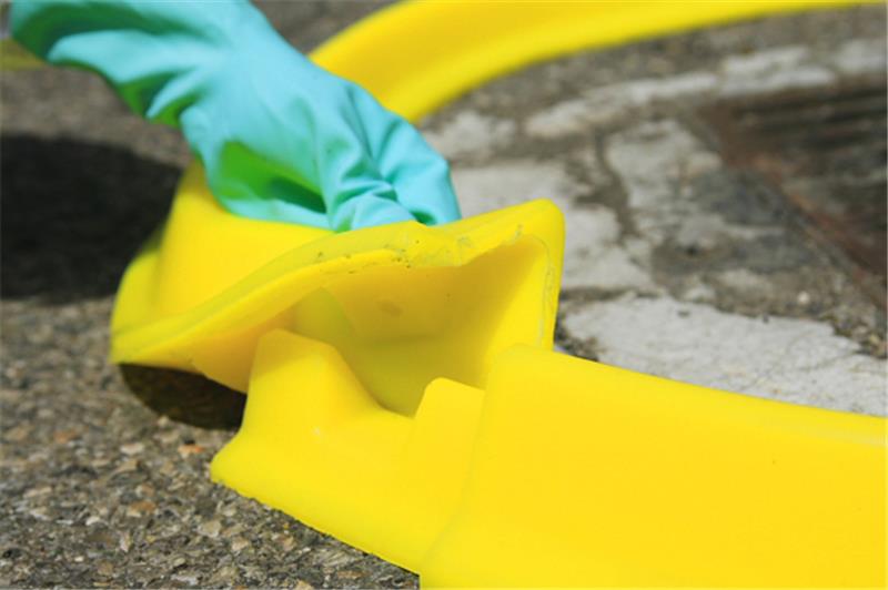 Barrage d'obturation jaune Plastibarre en polyuréthane bloquant une fuite de liquide devant un fût bleu.