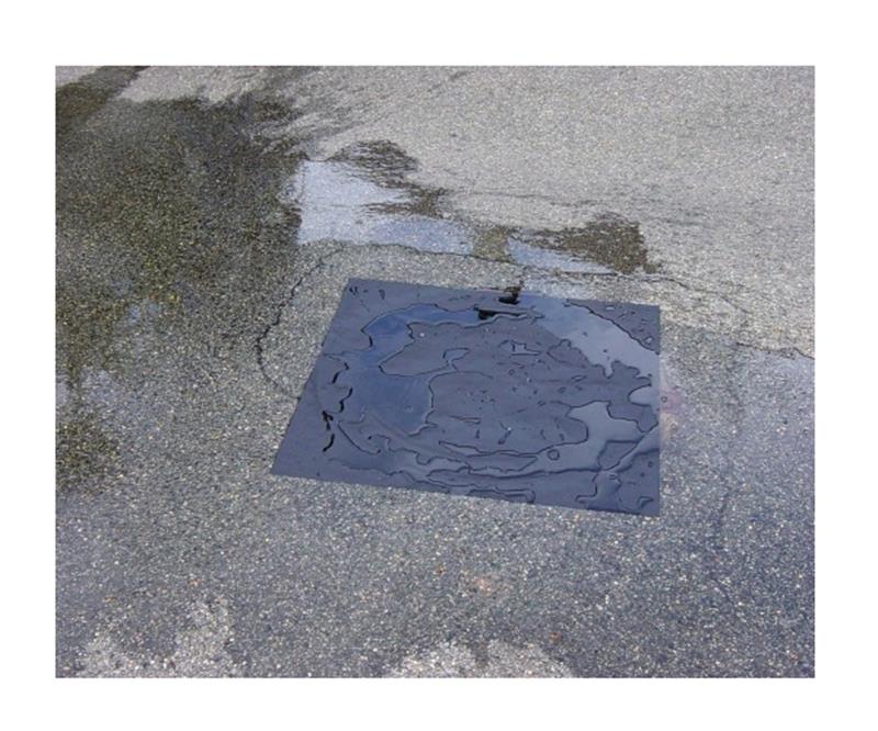 Plaque d'obturation carrée noire à usage unique 90cm x 90cm positionnée sur une grille d'égout.