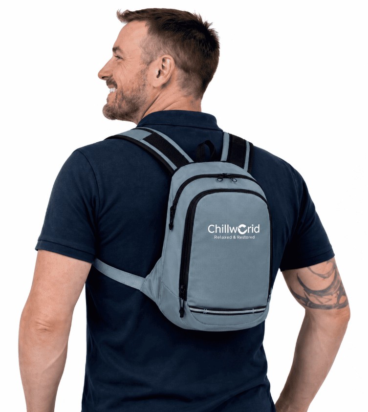 Vue arrière d'un homme souriant portant le petit sac à dos de thermorégulation gris NomadPRO de Chillworld.