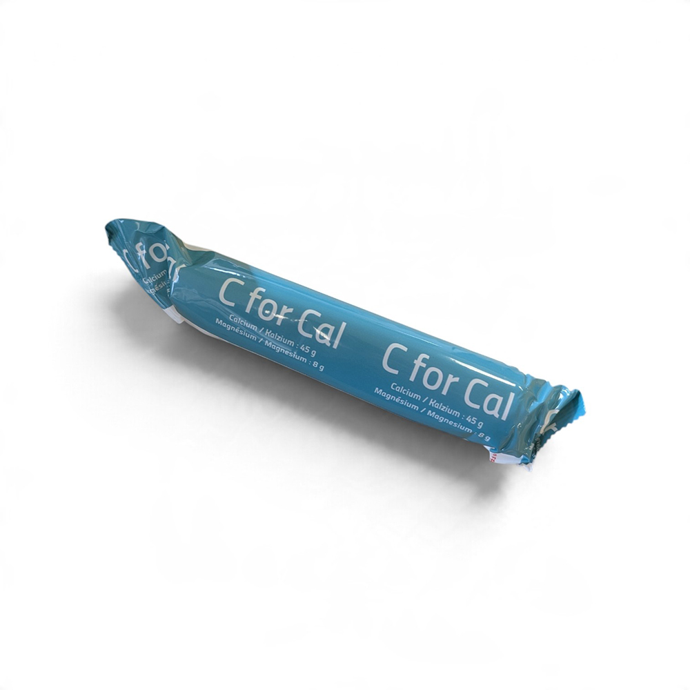 Boîte bleue et blanche de bolus C for Cal pour vaches laitières, accompagnée d'un bolus cylindrique beige au premier plan.